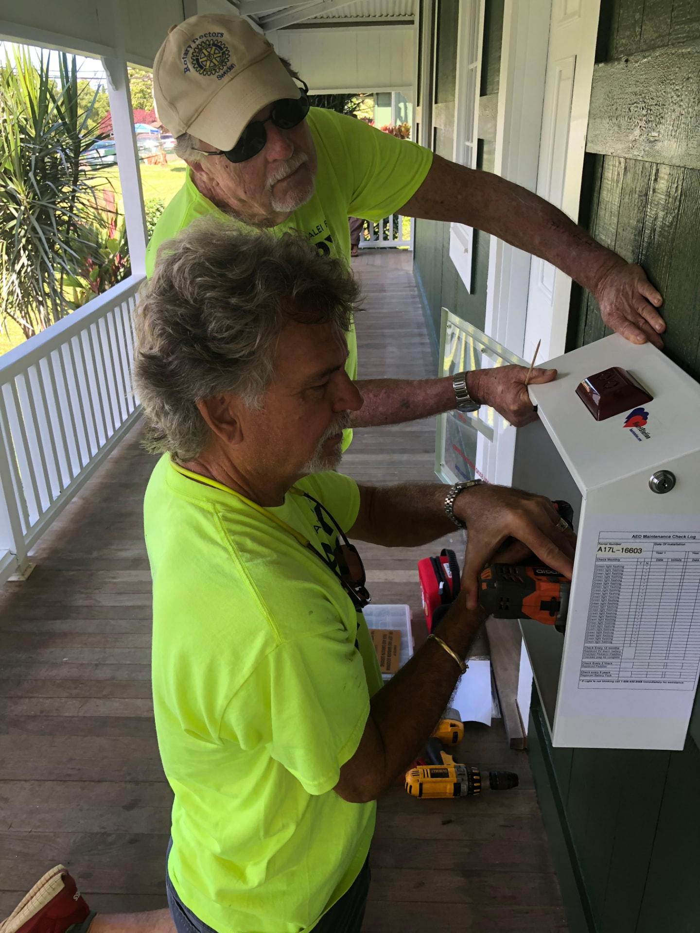 Rotary members installing an AED cabinet on the North Shore